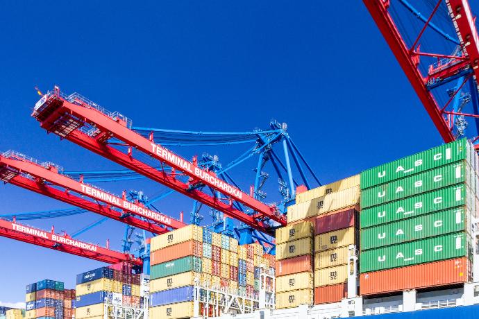 red metal crane near blue and yellow cargo container van